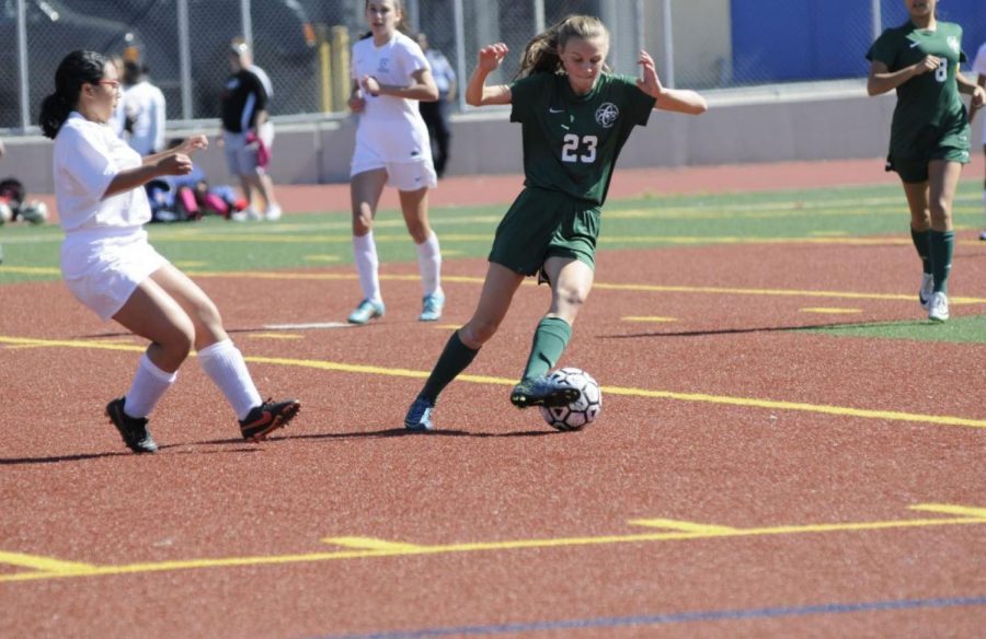 Varsity Soccer member Claire Glendening 18 swiftly dribbles the soccer ball across the field, and away from opponents during a game.