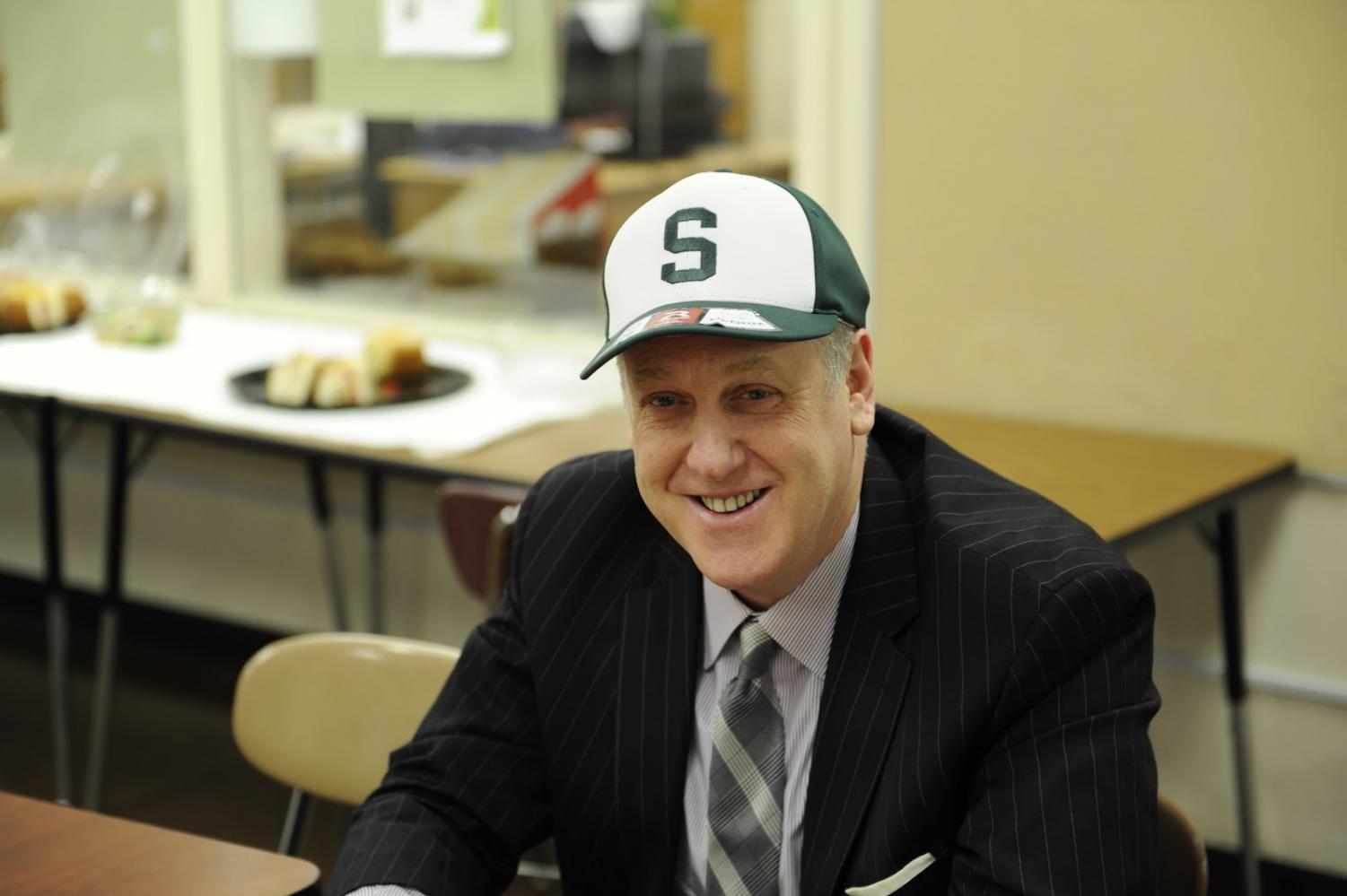 Michael Kay tries on a hat gifted to him by the Varsity Baseball team.