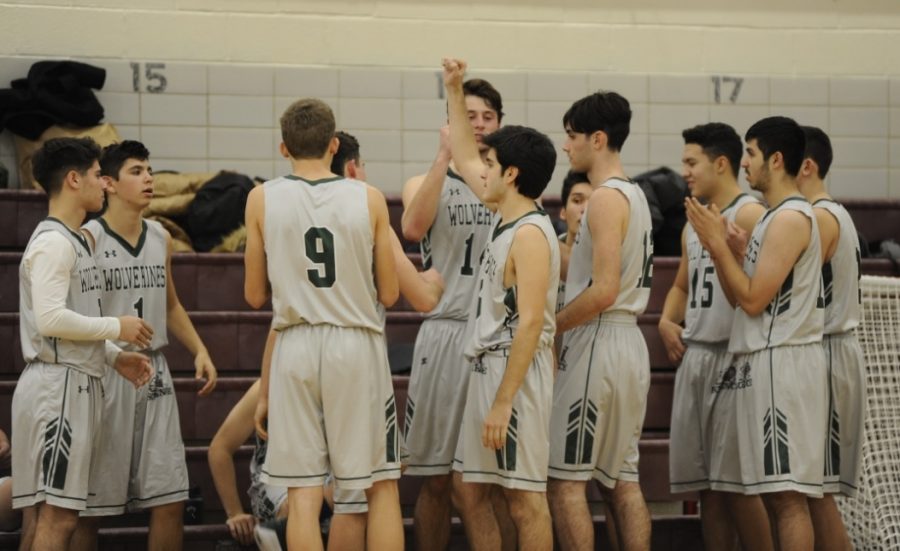 Boys+Varsity+Basketball+eam+members+gather+around+to+encourage+each+other+before+a+home+game.