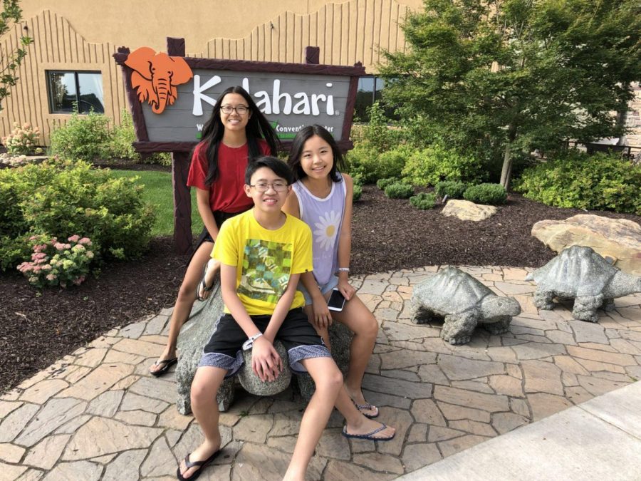 Sitting on a turtle in front of a conservation center, Joy, Eddy, and Julie Lin sit on a turtle on a family outing together.