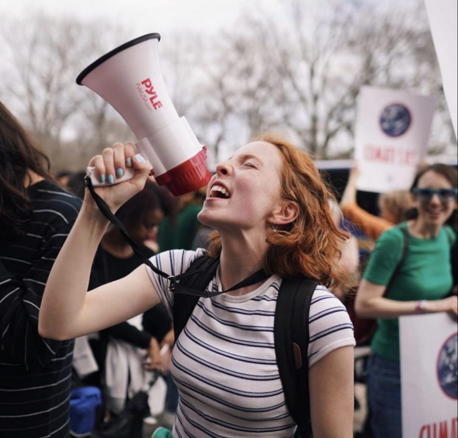 Climate activist and Bronx Science student Azalea Danes ’20 chants passionately into a megaphone during the March 15th, 2019 climate strike at Columbus Circle.