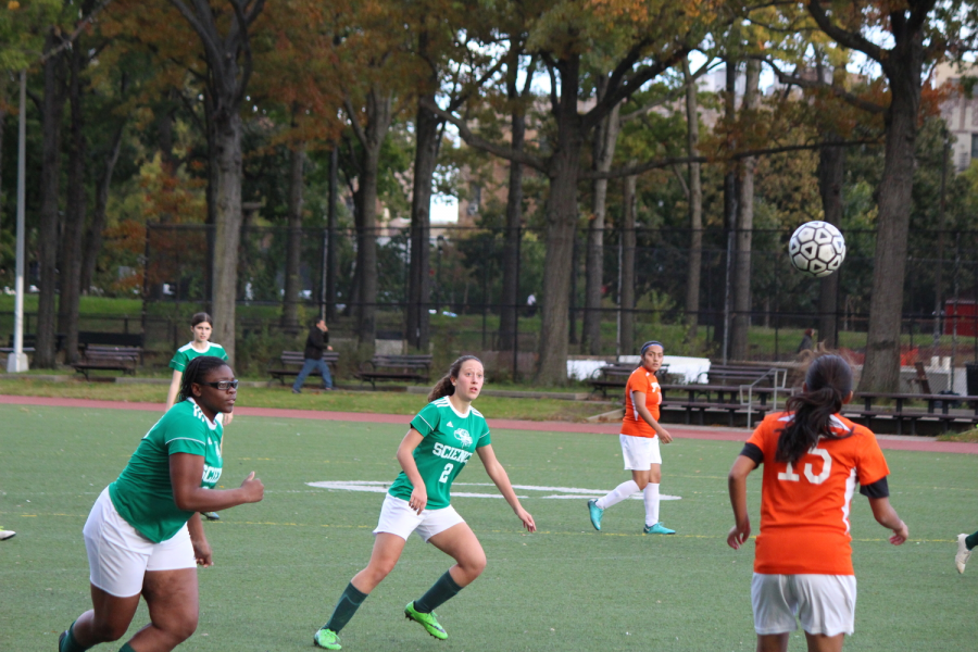 Members of the Bronx Science Girls' Varsity Soccer team lock their eyes on the ball while playing a game against another school. 