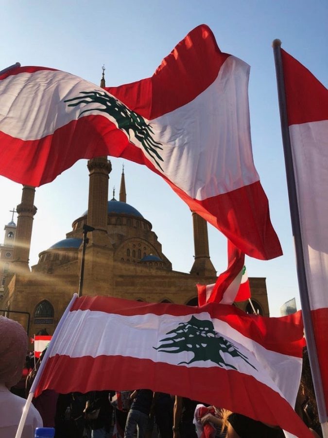 Lebanese flags wash the sky in red and white as protestors flood the streets of downtown Beirut.