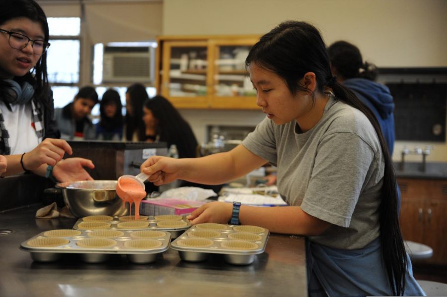 A student pours batter into a cupcake tray during an Edible Arts club meeting.