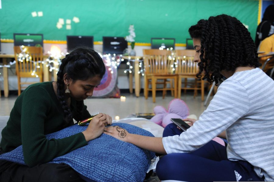 A member of the Muslim Student Association draws a henna tattoo on another student at their fundraiser.