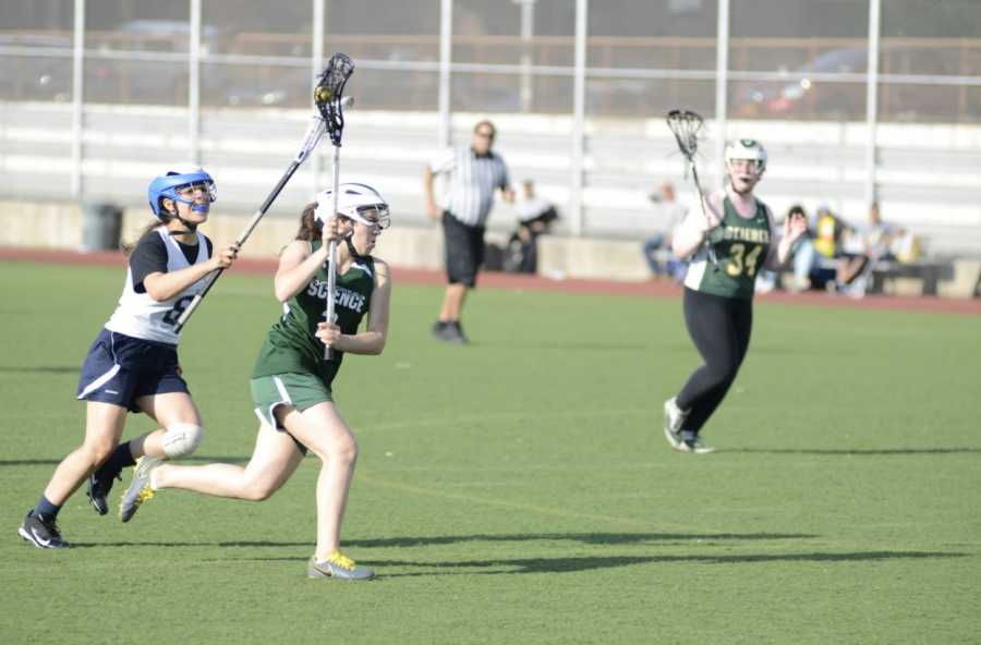 As Samantha Mayol ’22 runs towards the goal during a Girls Varsity Lacrosse meet, she looks for an opening to make her shot.
