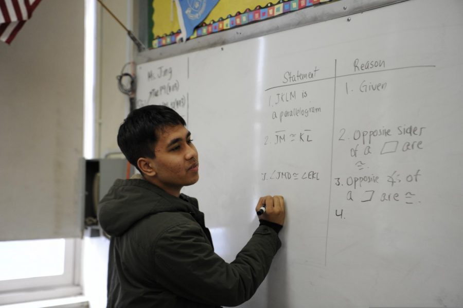 A ninth grader presents his work on the board in Geometry.