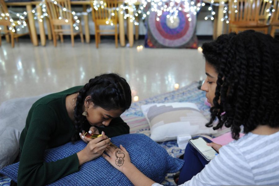 A student gives her peer a henna tattoo in Muslim Students Association.
