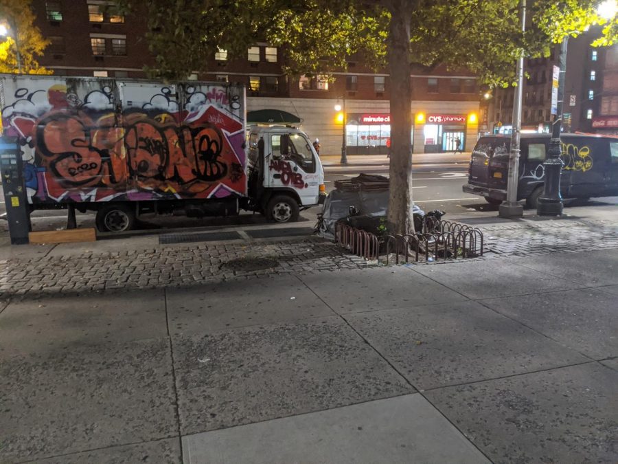 Temo Samson owns multiple fruit carts across Harlem. This includes the vacant fruit supply truck shown (on the left). Also shown is the empty space where one of his fruit carts used to be before it was packed away temporarily (to the center-right, around the front of the tree). “This was my source of income, and now it’s essentially gone,” said Samson.