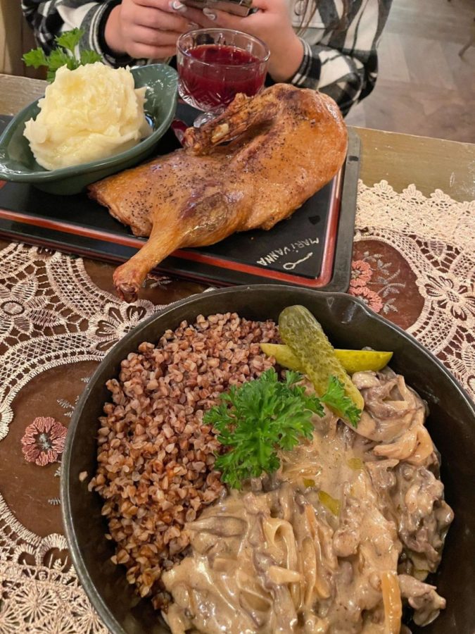 Pictured at the top is the Roast Duck with mashed potatoes and cranberry sauce, and pictured at the bottom is Beef Stroganoff with buckwheat and pickles, all served on a beautiful tablecloth at the Mari Vanna restaurant. 