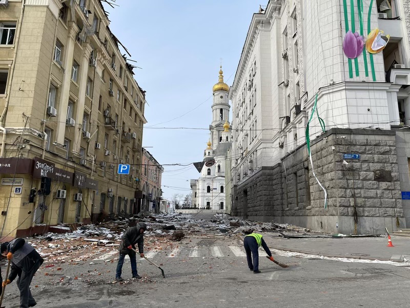 Ukrainian citizens clear rubble caused by Russian artillery off of a street in Kharkiv.