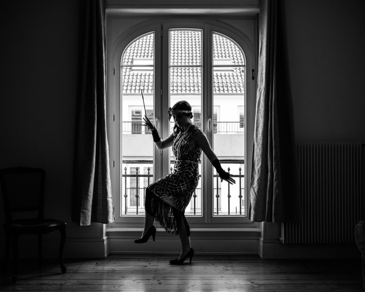 Pictured is a modern photographic representation of a flapper as she might have appeared at the time of the Harlem Renaissance. Here, she is seen dancing alone. ( Photo Credit: Carrie Borden / Unsplash)