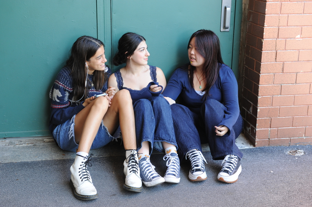 Students sit and chat outside of the cafeteria doors. 
