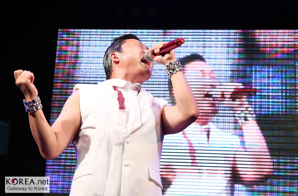 Here is PSY performing at Seoul College, Seoul just about two months after his hit song, Gangnum Style, debuted in July, 2012. His song criticizing the young people in the Gangnam district (part of Seoul) was an instant sensation.  (Photo Credit: Korea.net / Korean Culture and Information Service (Photographer name), CC BY-SA 2.0 , via Wikimedia Commons)