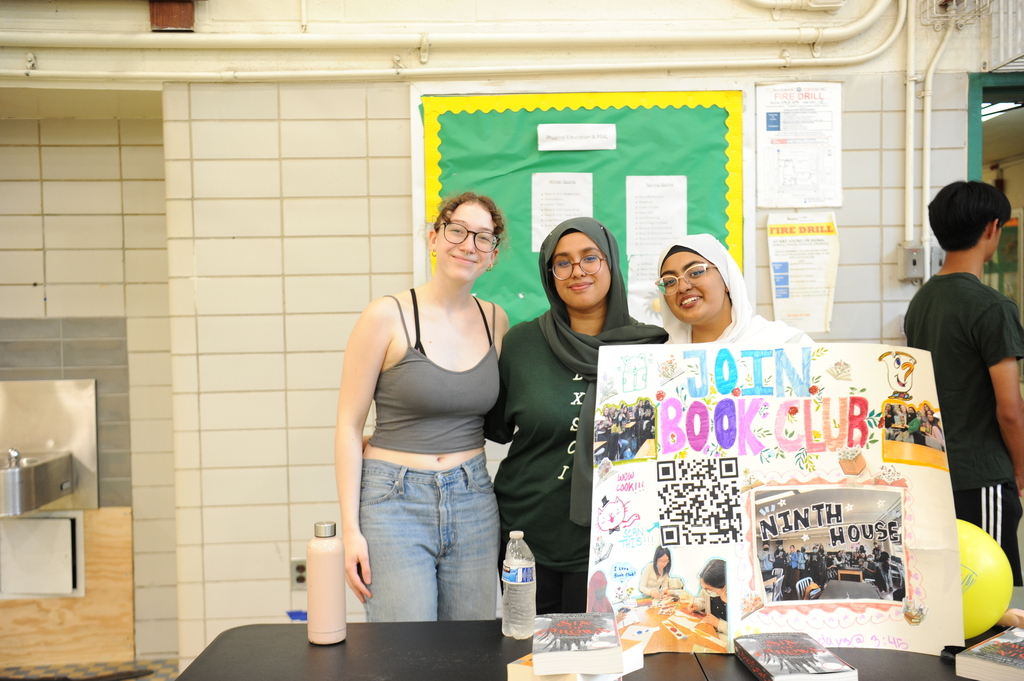 Three students from the Book Club showcase their poster, decorated with experiences from their meetings.