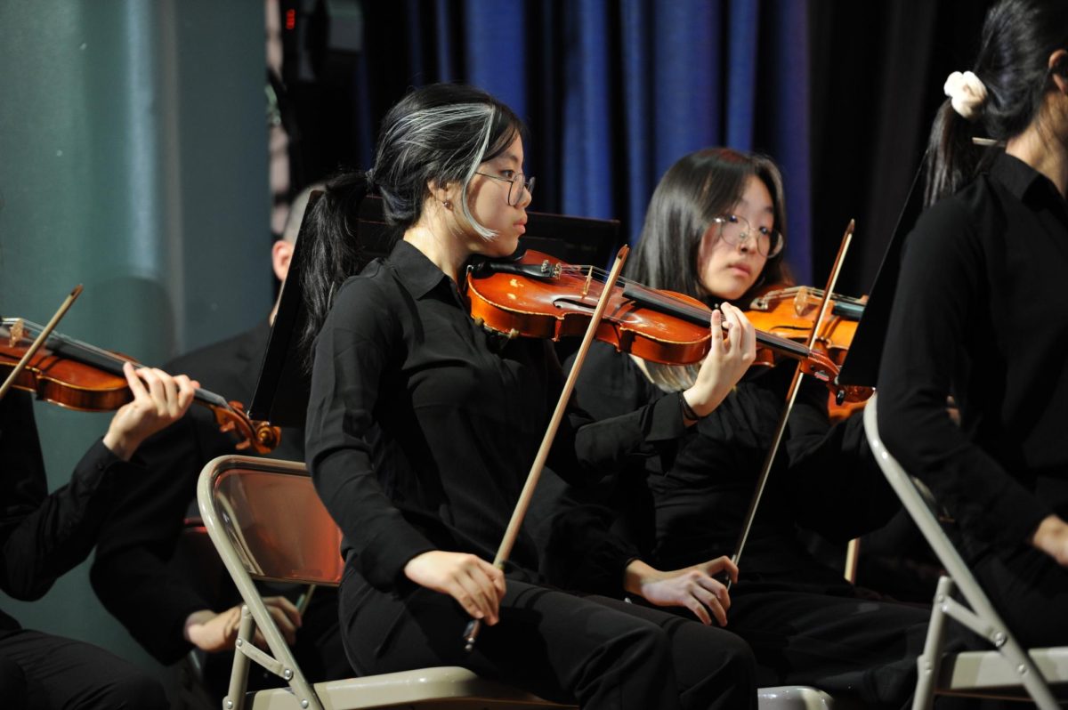 Here we see Erica Liu ’26 performing the violin alongside fellow students in the orchestra. 
