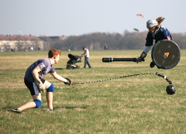 Here, during a game of Jugger, a player jumps to avoid a ball and chain attack by jumping over it, armed with a short sword and shield. (Photo Credit: Ruben Wickenhäuser, CC BY-SA 2.0 , via Wikimedia Commons)