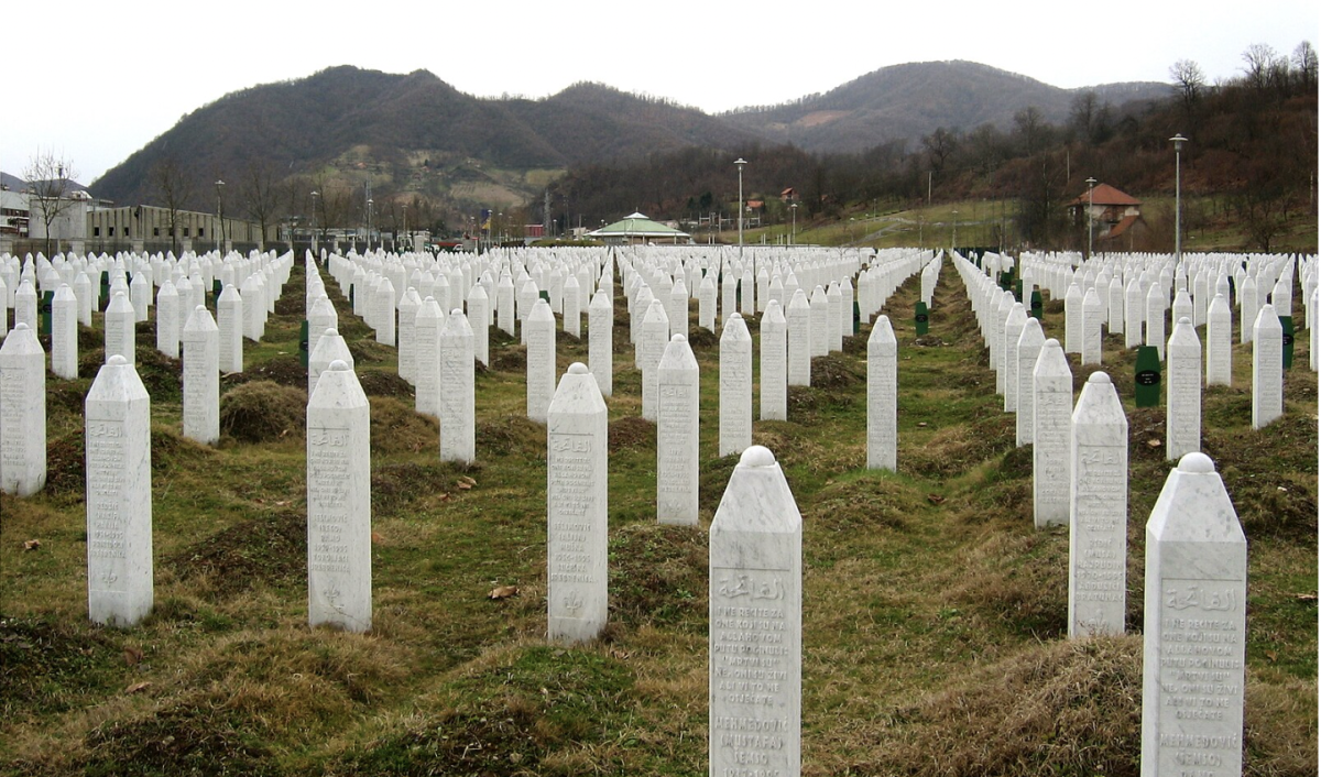 At the Potočari genocide memorial near Srebrenica, Bosnia & Herzegovina,  countless gravestones stretch across the entire field, serving as a stark and solemn reminder of the lives lost during the 1995 Bosnian genocide. (Photo Credit: Michael Büker, CC BY-SA 3.0 , via Wikimedia Commons) 