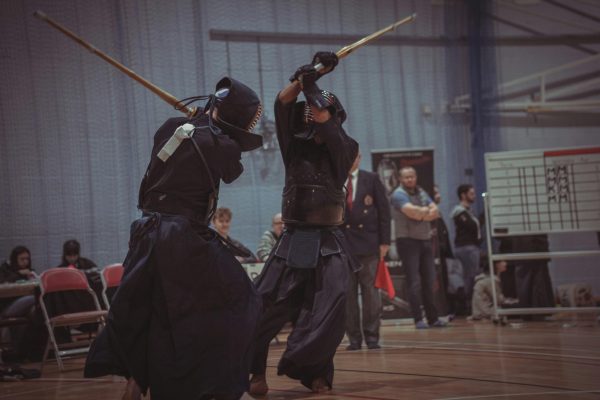 Pictured are two kendōka with their shinai, charging up a strike, during the Welsh Cup in 2024. (Photo Credit: Anna Saveleva / Unsplash)
