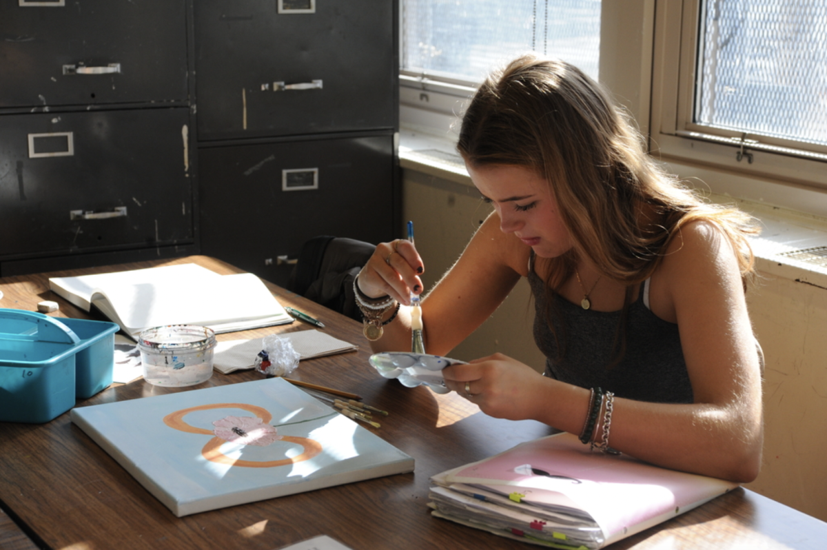 Renner Ashley ‘26 mixes colors for her floral canvas painting in the back of the classroom.
