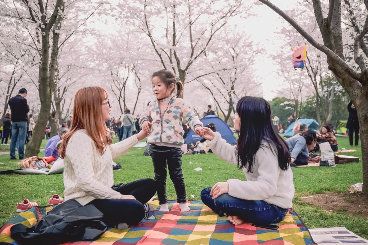 A family holds hands with a toddler, who is excited to see what life has to offer. (Photo Credit: Jerry Wang / Unsplash)
