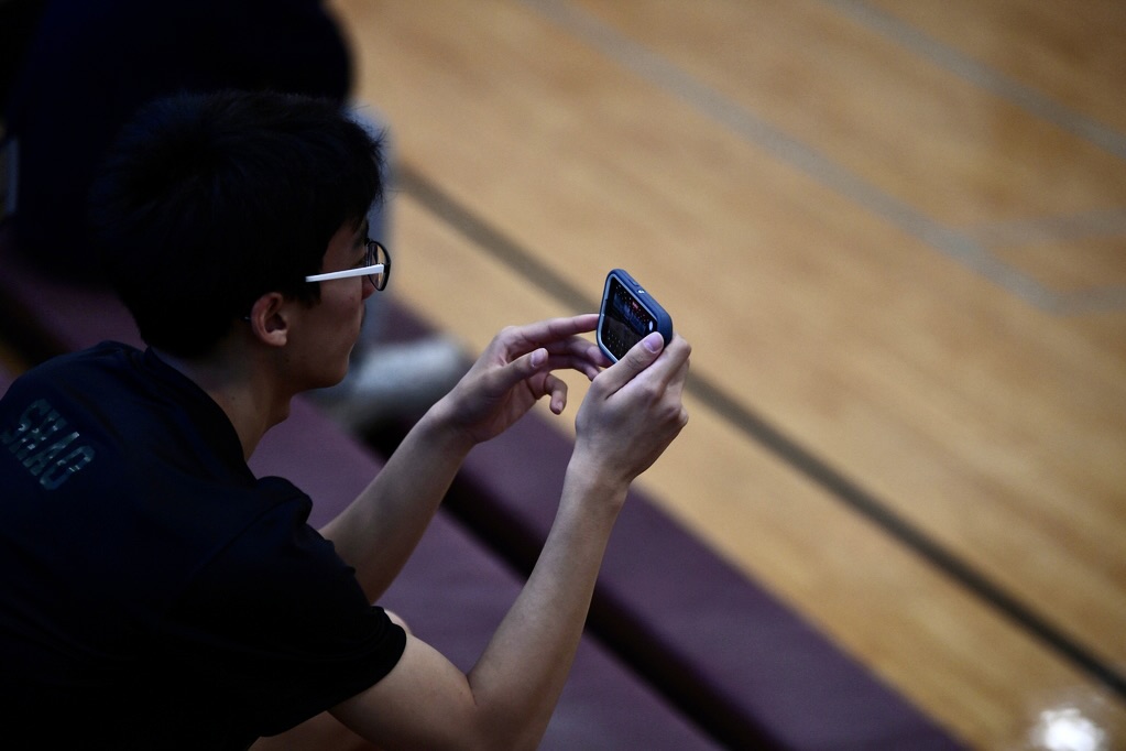 An onlooking student films a tense match.  