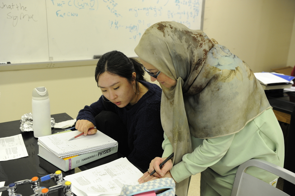 Two female students work together to review worksheets in AP Physics C.