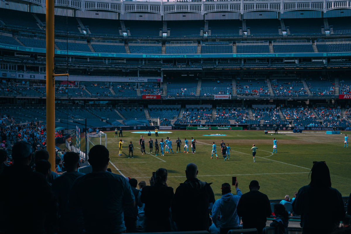 Pictured is New York City FC (players in blue) playing in a converted Yankee Stadium; note the odd and uneven shape of the pitch due to the stadium originally being intended for baseball. (Photo Credit: Benjamin Cutting / Unsplash)