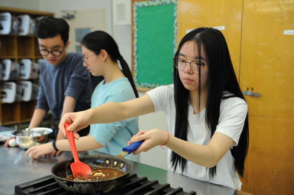 A student tends to the chocolatey contents of her saucepan.