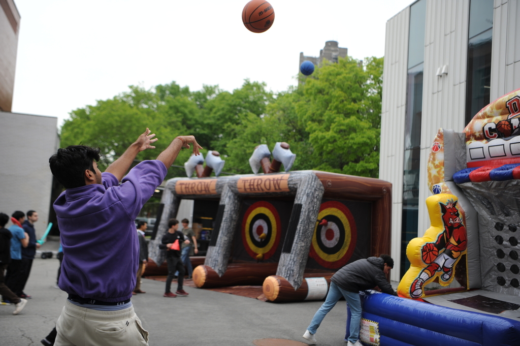 A student takes a three-pointer shot towards the bouncy house basketball hoop. 