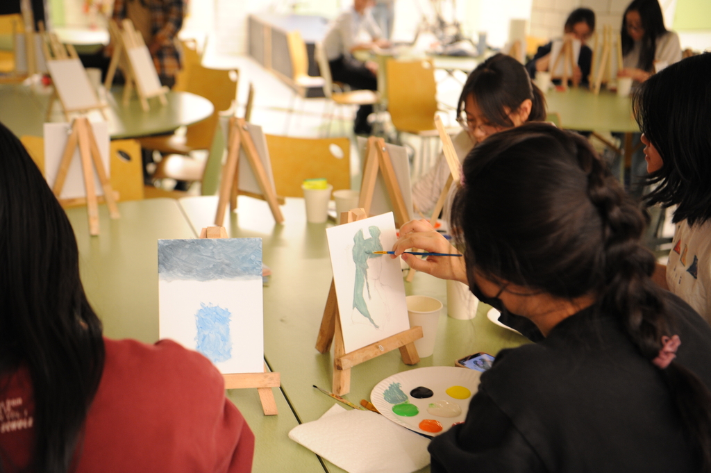 A group of friends sit at a circular table in the cafeteria to chat while they paint their different inspirations during the event.