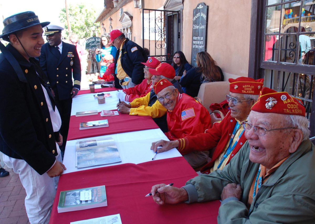 Pictured is an event that raised awareness about the Navy’s Navajo Code Talkers who served in World War II. Here, they have a chat with an attendee. The Navajo Code Talkers used their native language to develop an unbreakable code to prevent U.S. government plans from being leaked. (Photo Credit: U.S. Navy photo by Mass Communication Specialist 1st Class Eric Brown, Public domain, via Wikimedia Commons)