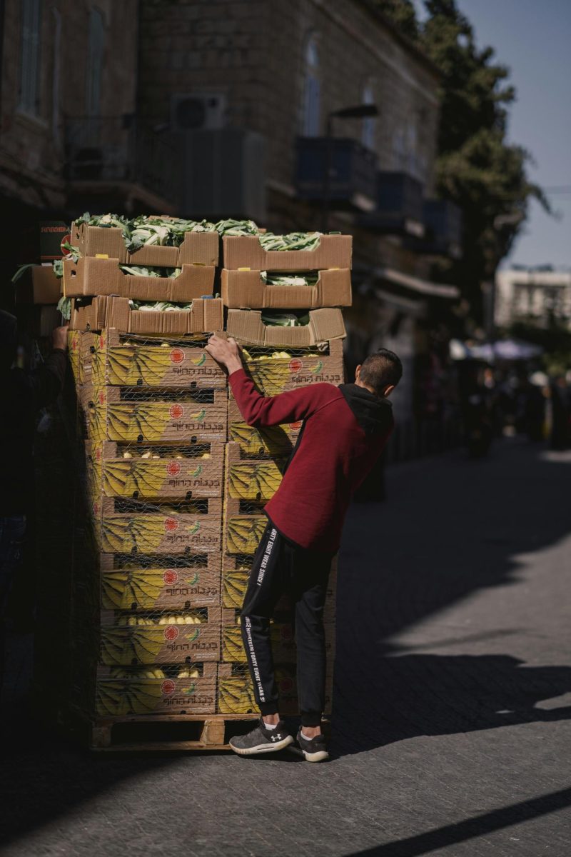 This photograph depicts a local inhabitant in a Jerusalem market district, serving as a visual entry point into the systemic challenges of food insecurity and the precarious nature of food sovereignty in regions where historical conflict and modern economic barriers limit consistent access to affordable, nutritious resources. (Photo Credit: Levi Meir Clancy / Unsplash)