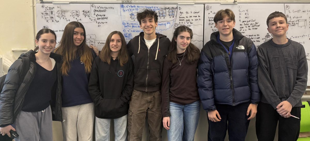 Here, a group of student tutors stand together in a classroom following a session of 'Science For Bronx.' Behind them on the whiteboard is work from the lesson that they just completed teaching. (Photo Credit: Science For Bronx; used by permission)